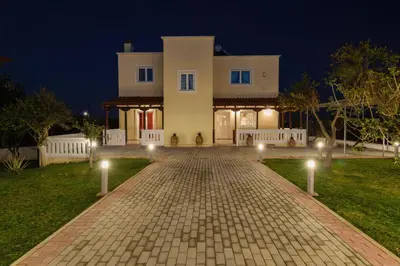 a large white house with a driveway at night at Villa Albion in Kolymvari
