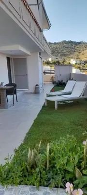 a house with a patio with chairs and a lawn at Sunrise Apartment 2 in Souda
