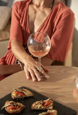 a woman sitting at a table with a glass of wine at Esperanto Seafront suites in Agia Marina Nea Kydonias