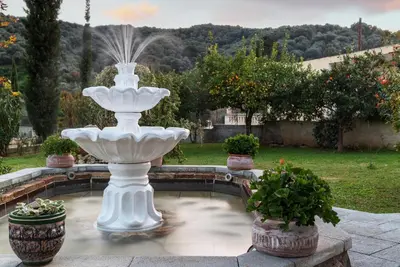 a white fountain in a garden with potted plants at Villa Kalaitsidi - plunge pool, gym and unique gardens in Skinés