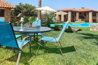 a table and chairs in a yard with a pool at Villa Milon by PosarelliVillas in Skinés