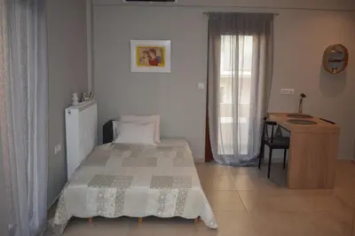 a bedroom with a bed and a desk and a window at Saxon's Apartment in Chania Town
