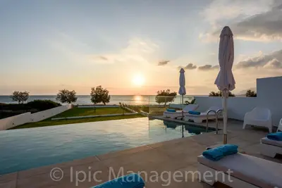 a villa with a pool and the ocean at sunset at Seafront VILLA PELAGIA SUPERB New listing in Chania Town