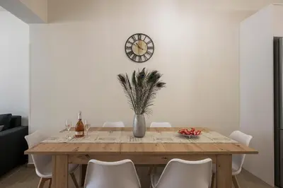 a dining room table with chairs and a clock on the wall at Cataleya Villa Chania in Daratso