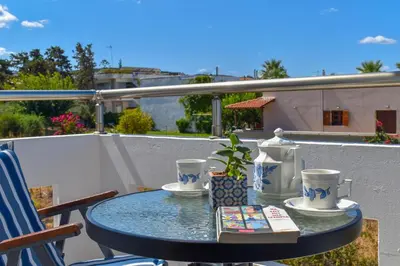a table with a book and cups on a balcony at Giannis & Maria Gramvousaki Apts in Agia Marina Nea Kydonias