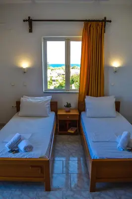 two beds in a room with a window at Giannis & Maria Gramvousaki Apts in Agia Marina Nea Kydonias