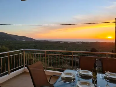 a table and chairs on a balcony with a sunset at New Villa Kalimera, view to Falasarna beach in Plátanos