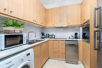 a kitchen with wooden cabinets and a washer and dryer at DIMITRA apartment with private pool and sea view -the ground floor of a two storey building in Daratso