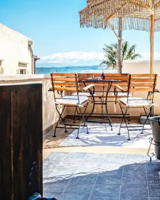 a patio with a table and chairs on the beach at Sclopa The Laography Project in Kolymvari