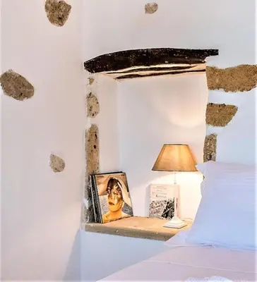 a bed with a table with a lamp and a picture at Sclopa The Laography Project in Kolymvari