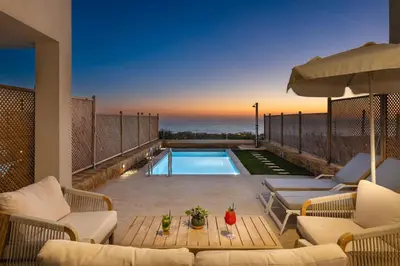 a patio with a pool and chairs and an umbrella at Diamond Star Hotel in Falasarna