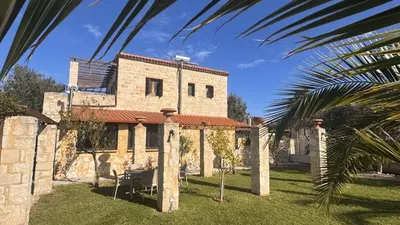 a stone house with a palm tree in front of it at World Villa in Tavronitis