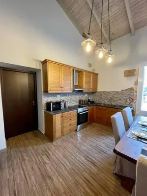 a kitchen with wooden cabinets and a table with chairs at Villa Eftychia Serene Getaway with Hot Tub in a Quiet Location in Kissamos