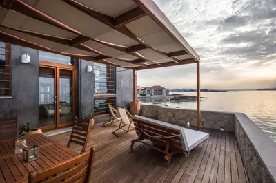 a deck with chairs and a bench on the water at Villa Yasemi panoramic sea view in Chania Town