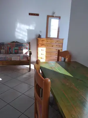 a dining room with a wooden table and a bed at Ton Mari Apartments in Palaiochóra