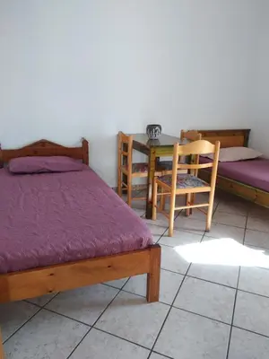 a bedroom with two beds and a table and chairs at Ton Mari Apartments in Palaiochóra