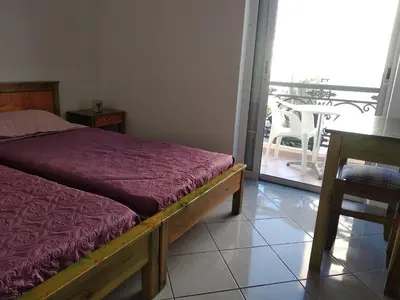 a bedroom with a bed and a table and a balcony at Ton Mari Apartments in Palaiochóra