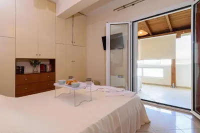 a bedroom with a white bed and a table at Central penthouse in quiet neighborhood near sandy beach in Chania Town