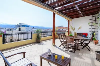 a patio with tables and chairs on a balcony at Central penthouse in quiet neighborhood near sandy beach in Chania Town