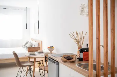 a kitchen with a sink and a table with a bed at Astra boutique suites at Agia Marina Beach in Agia Marina Nea Kydonias