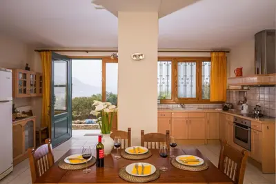 a kitchen with a wooden table with chairs and a large window at Seaview Villa Sofia ' Top destination ' in Kissamos