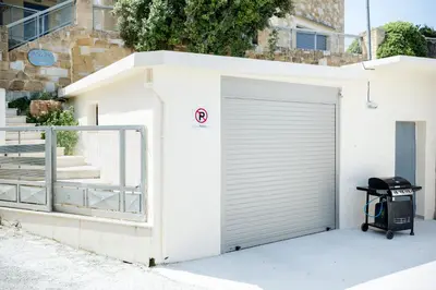 a white garage with a door and a trash can at Petros Luxury Traditional House - Villa in Kissamos