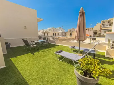 a patio with a table and a umbrella and chairs at Fully renovated apartment in the city centre with roof garden! 3 minutes from the bus station and 6 minutes from the old town in Chania Town