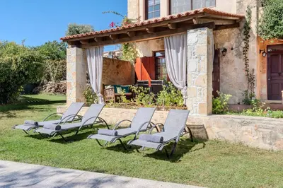 a group of chairs sitting on the grass in front of a house at Skine Dream Villa in Chania Town