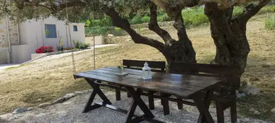 a wooden picnic table in front of a tree at nafsikacottagehouse in Kissamos
