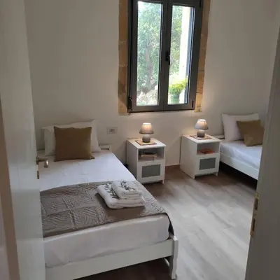 a white bedroom with two beds and two windows at nafsikacottagehouse in Kissamos