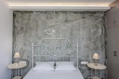 a bedroom with a bed with two tables and a wall at Glaros Studios in Kalamaki Chanion