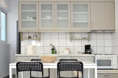 a kitchen with white cabinets and a table with chairs at Glaros Studios in Kalamaki Chanion