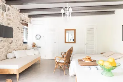 a white living room with a table and a couch at Feána Home by 8essentially in Psathoyiánnos