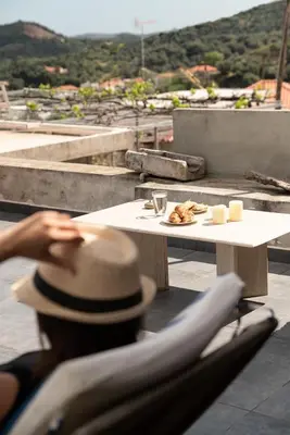 a person wearing a hat sitting at a table on a roof at Feána Home by 8essentially in Psathoyiánnos