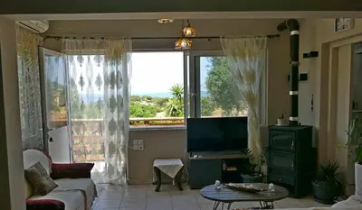 a living room with a couch and a large window at Kedrodasos House in Elafonisi