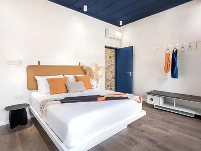 a bedroom with a large white bed with orange pillows at New Boutique Venetian apartments - La Casa Nove in Chania Town