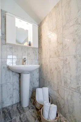 a bathroom with a sink and a mirror and towels at Beach House Kalamaki steps away from the beach in Galatás