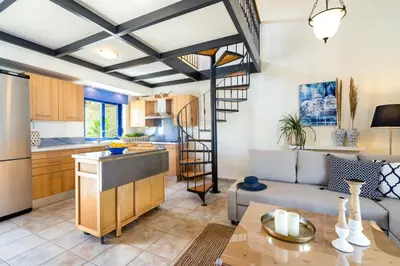 a kitchen and living room with a spiral staircase in a room at Beach House Kalamaki steps away from the beach in Galatás