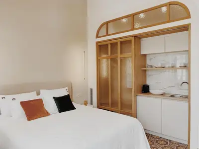 a bedroom with a white bed and a kitchen at Kale Kapi City Living in Chania Town