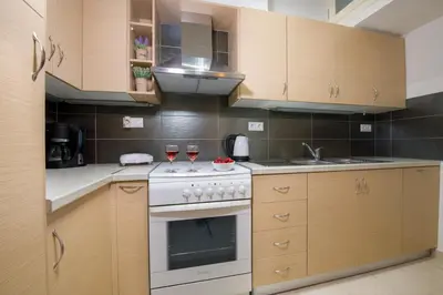 a kitchen with a stove and two glasses of wine at Erontas Apartment in Palaiochóra