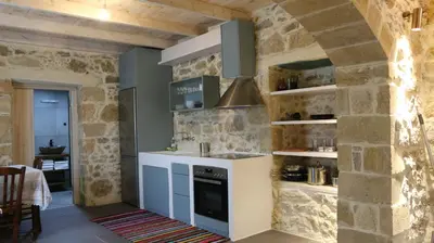 a kitchen with a stone wall and a stove at Mouri Village in Aïkiryiánnis