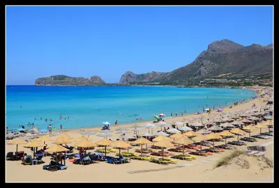 a beach with many umbrellas and people in the water at Mouri Village in Aïkiryiánnis
