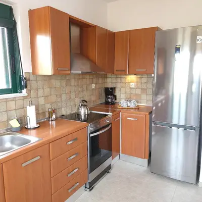 a kitchen with wooden cabinets and a stainless steel refrigerator at Paradisos Villa - Chania, Crete in Litsárdha