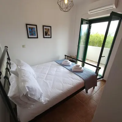 a bedroom with a bed with white sheets and a window at Paradisos Villa - Chania, Crete in Litsárdha