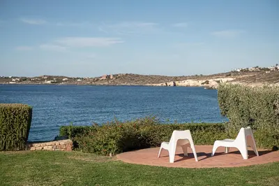 two white chairs sitting next to a body of water at VILLA NIBA in Kalathas