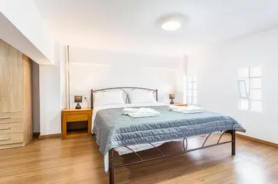a white bedroom with a bed and a wooden floor at Neva's Apartment's in Center Chania 1 2 in Chania Town