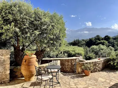 a patio with a table and chairs and a large vase at Maison Théia, entre mer et montagne Samonas in Samonás