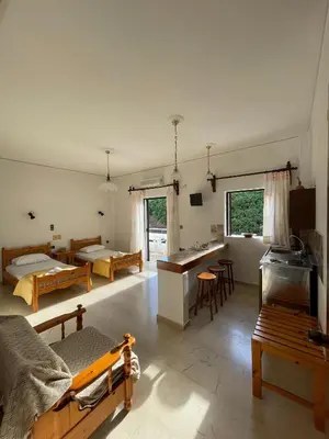 a bedroom with two beds and a kitchen and a room with tables at Aeolos Apartments Kolymbari in Kolymvari