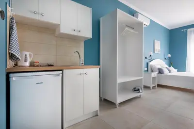 a kitchen with white cabinets and a bathroom with a bed at Evi Boutique Rooms in Galatás