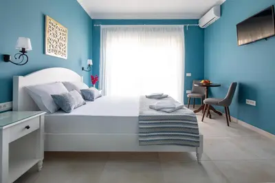 a bedroom with a white bed and blue walls at Evi Boutique Rooms in Galatás